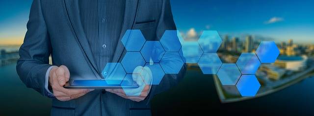 Business professional holding a tablet with digital hexagon technology overlay against a city skyline